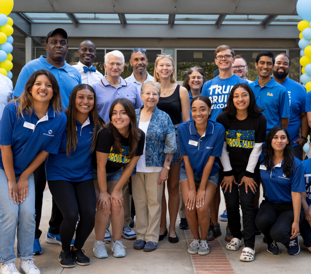 Group shot of students, faculty, and staff smiling on a patio decorated with blue and gold balloons. Amongst them, EVCP Hunt, Chancellor Block, and Mrs. Block.